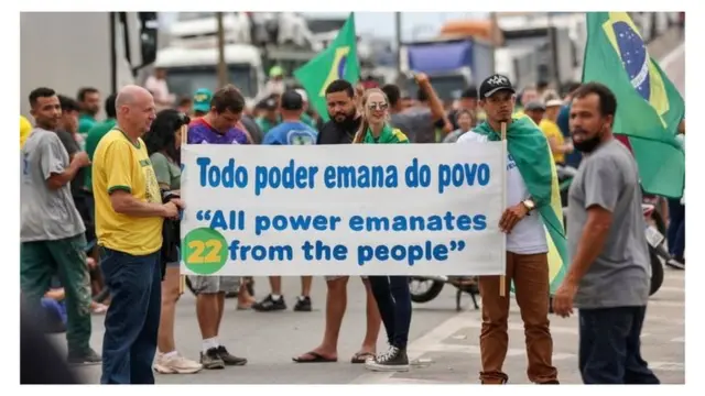 Manifestantes bolsonaristas com cartaz e número 22 , vestidos7upbetverde e amarelo, fecham rodovia