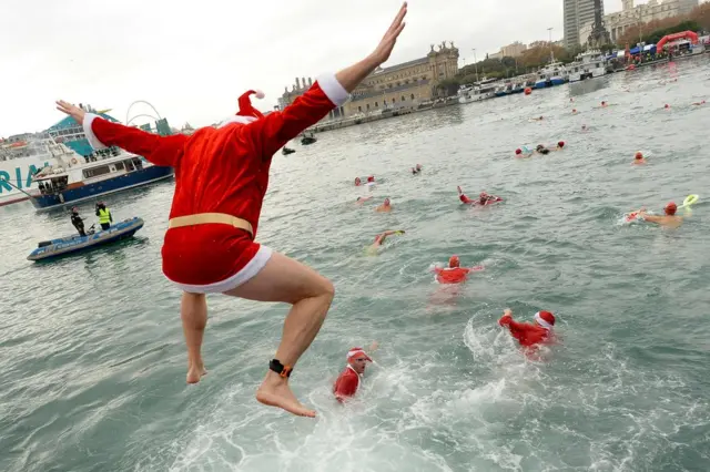 A participant in a Santa Claus costume jumps into the water during the 108th edition of the "Copa Nadal" (Christmas Cup) swimming competition in Barcelona's Port Vell on December 25, 2017