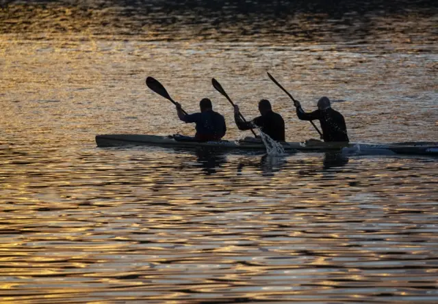 Canoeists paddle together in the twilight.
