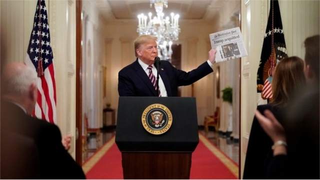 ترامب يحمل صحيفة تحمل عنوان خبر تبرئته