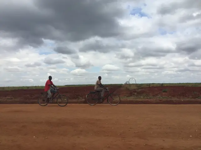 Garotos andambikefrente a um campo