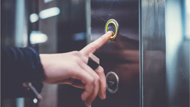 Mujer oprimiendo el botón del ascensor