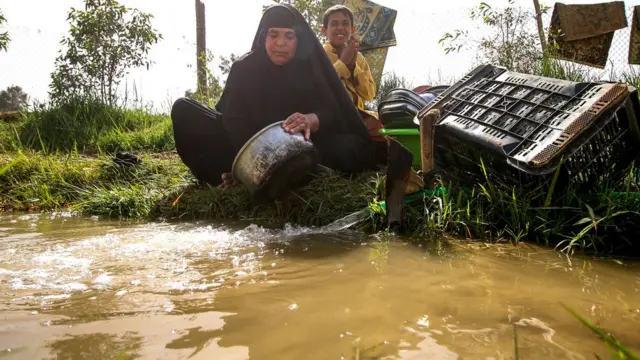 Une femme lave des casseroles et des ustensiles dans un jet d'eau dans le village de Sayyed Dakhil, à l'est de la ville de Nasariyah, à quelque 300 kilomètres au sud de Bagdad, le 20 mars 2018.