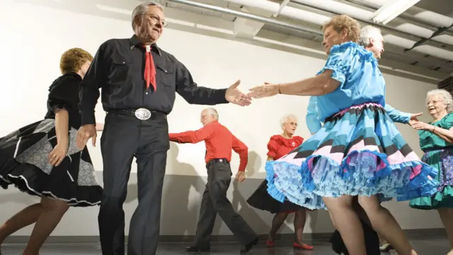 Personas bailando en grupo intercambiando parejas en un círculo