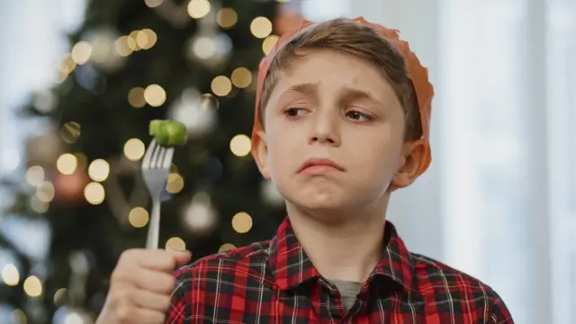 Мальчик с кислой миной и брюссельской капустой на вилке