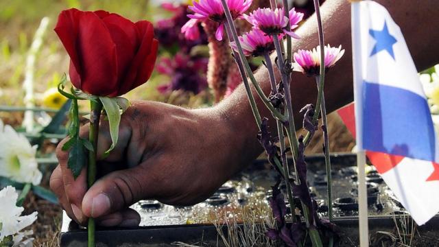 Un niño con una rosa sobre la tumba de un soldado muerto el 20 de diciembre de 1989