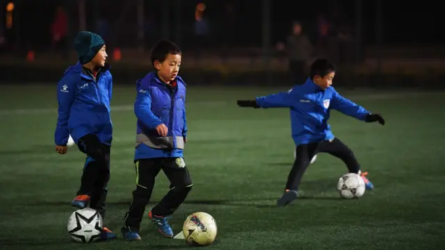 Crianças chinesas jogando futebol