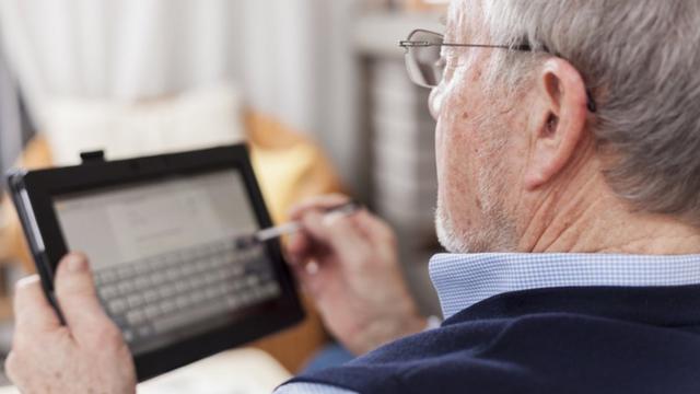 Homem idoso mexendo no tablet