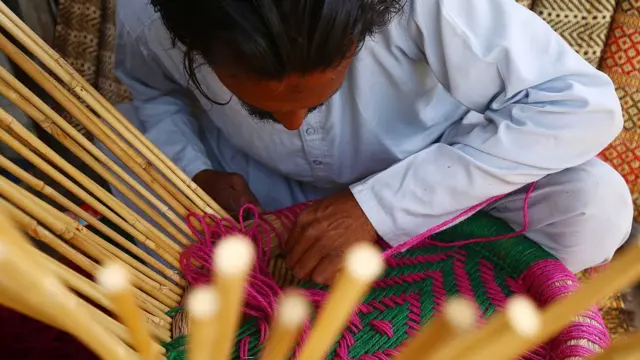 पारंपरिक स्टूल बनाता हुआ एक व्यक्ति