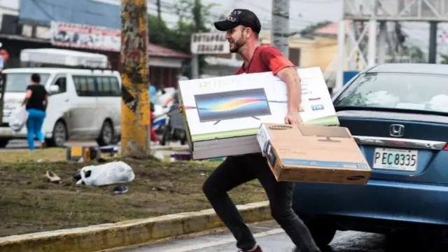 Un hombre transporta una televisión.