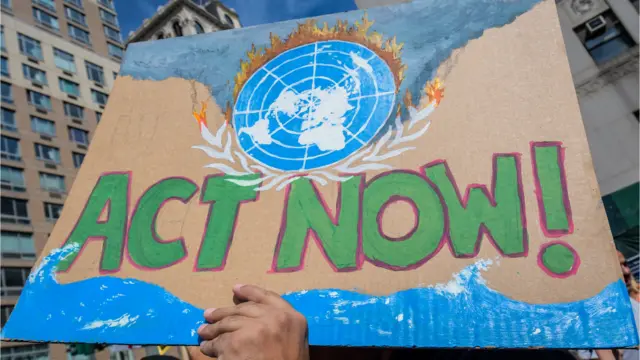 Papan protes bertulisan "Act Now!"