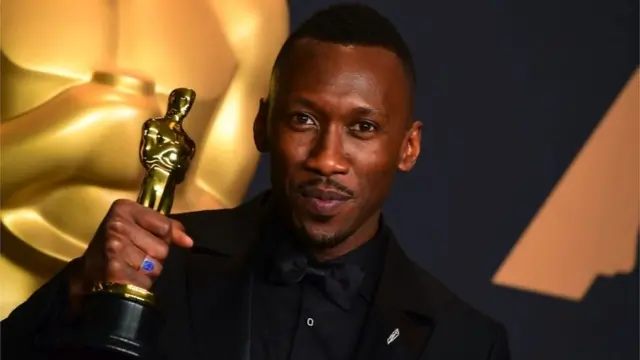Mahershala Ali holding an Oscar