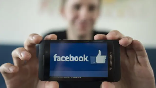 મોબાઇલમાં ફેસબુકની એપ સાથે વ્યક્તિ