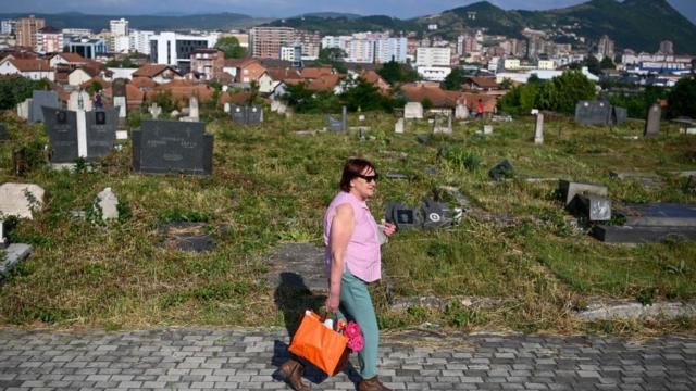 Una mujer visita un cementerio en la ciudad étnicamente dividida de Mitrovica, en Kosovo.