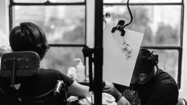 Ana Estrada siendo tatuada en un brazo.