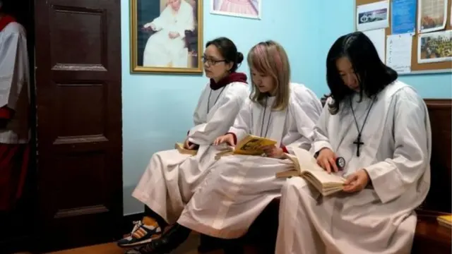 Người Công giáo Trung Quốc ở Thượng Hải ngồi đợi buổi lễ Phục sinh bắt đầu dưới bức ảnh Giáo Hoàng John Paul Đệ Nhị và Đức mẹ Đồng trinh.