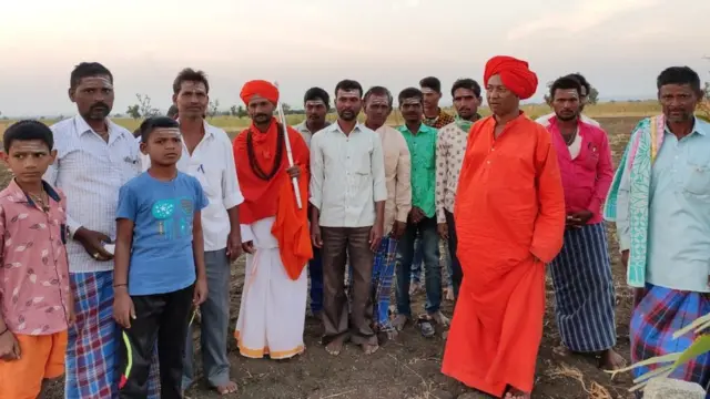 मध्यभागी भगवी शाल आणि पांढरी धोतर परिधान केलेले दिवान शरिफ