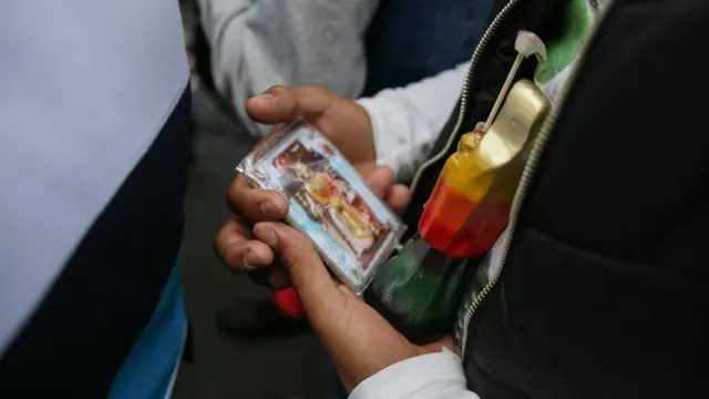 Mujer sostiene estampa con Santa Muerte.