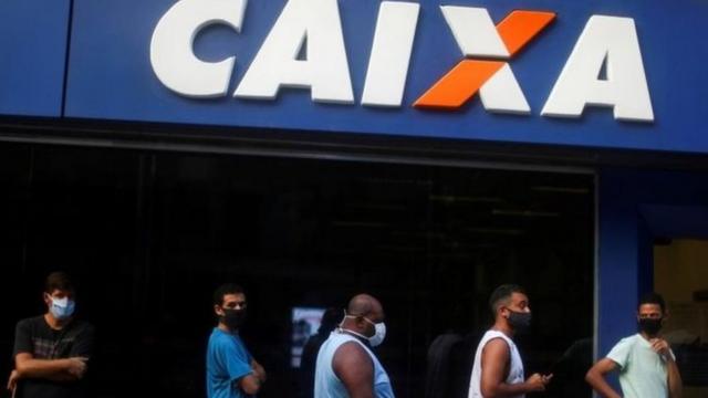 Pessoasbolão caixa pela internetmáscara aguardam na fila da Caixa Econômica