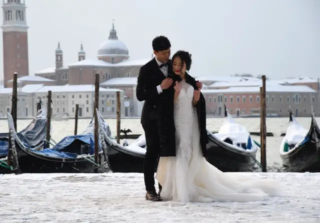 زوجان يلتقطان صور زفاف في ميدان القديس مرقس بمدينة البندقية في إيطاليا في أعقاب هطول الثلوج خلال الليل.
