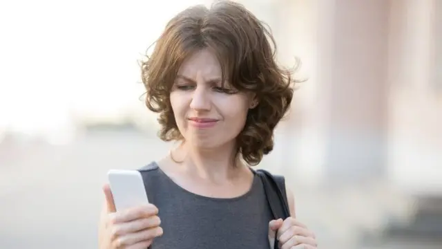 chica mirando celular con cara de asco