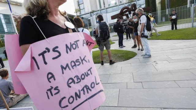 Mulher com cabelos grisalhos e sem máscara segura cartaz,horários de apostas on lineárea aberta e pavimentada, dizendo: "It's not about the mask, it's about control"