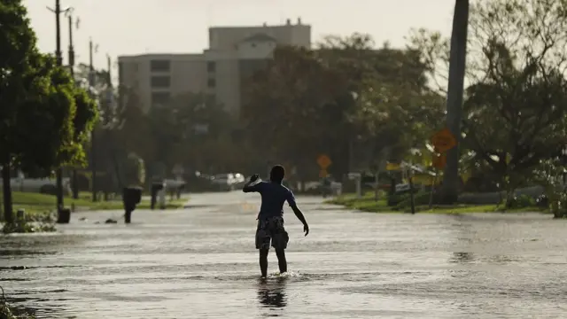 Jovem anda por rua inundada1xbet saque mínimoNaples, na Flórida