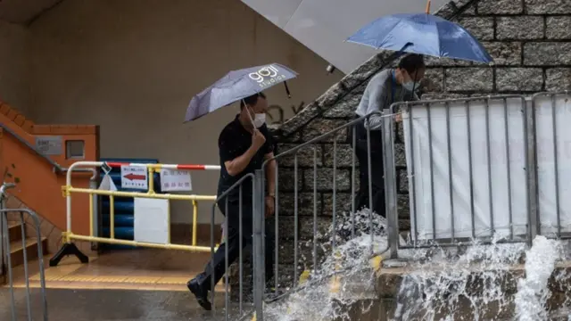 Two men walk past an overflowing manhole during a rain storm in Hong Kong.