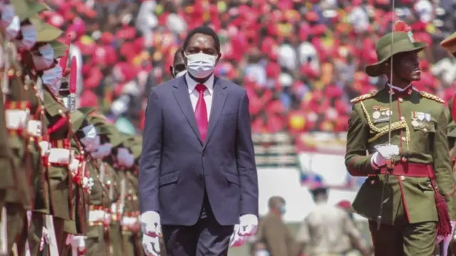 Hichilema as e dey pass between soldiers