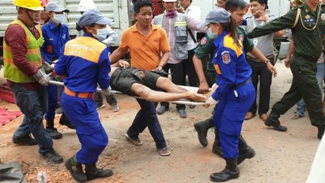 A Cambodian rescue team carries a wounded worker from the building