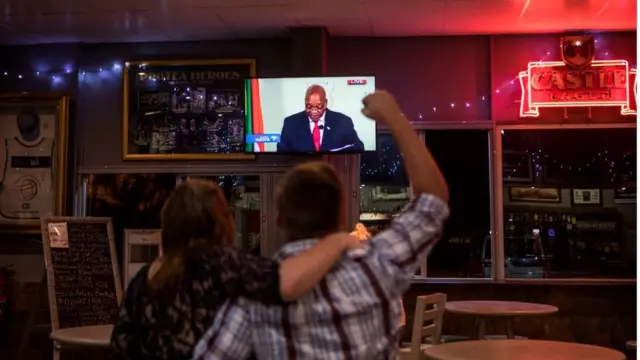 Awọn ọkunrin kan ati obinrin kan n wo Jacob Zuma lori mohunm,aworan