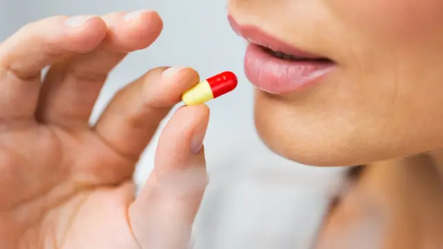Mujer ingiriendo una píldora.