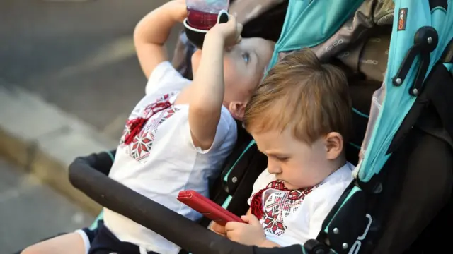 Маленькие близнецы. Одни из них смотрит в телефон