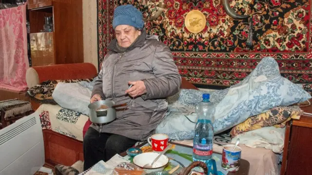 Мешканка Харкова сидить у квартирі одягнута, після того, як її будинок постраждав від обстрілів