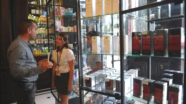 Una vendedora de perfumes con un cliente.