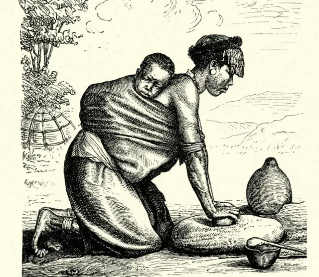 Mujer moliendo granos de rodillas, con un bebé en su espalda