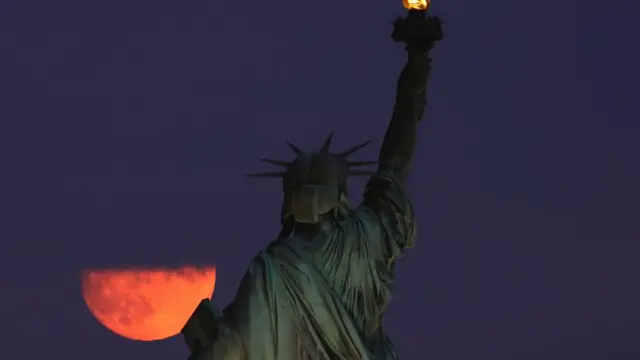 Осетровий місяць сходить у хмарах біля статуї Свободи в Нью-Йорку