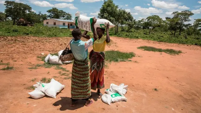 Deux femmes en Zambie portent des sacs de nourriture distribués par des organisations humanitaires en janvier 2020