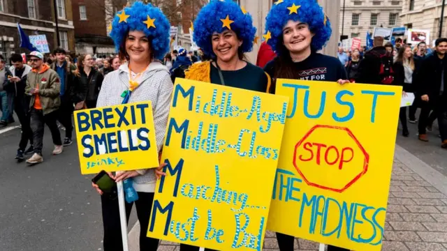 Tres manifestantes con pancartas