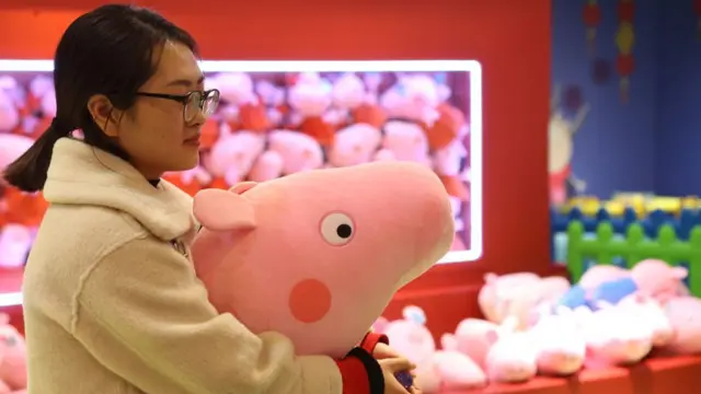 mulher com pelúcia da Peppa pig