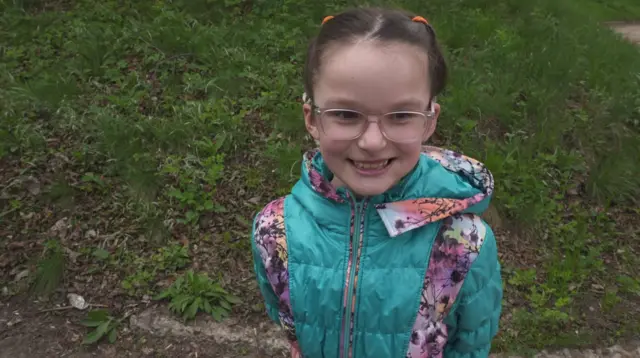 طفلة بنظارات تبتسم.