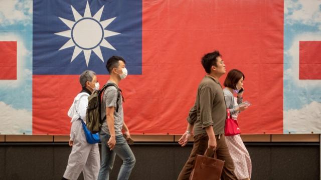 台北街頭路人走過一面印上青天白日滿地紅旗的橫幅（6/4/2023）