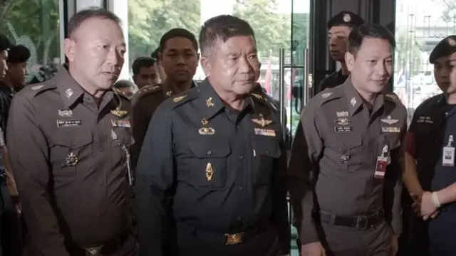 พล.ท. มนัส คงแป้น (คนกลาง) อดีตผู้ทรงคุณวุฒิกองทัพบก ผู้ต้องหาคดีขบวนการค้ามนุษย์ เดินทางพร้อมด้วยนายทหารพระธรรมนูญ เข้ามอบตัวกับ ผบ.ตร. ที่สำนักงานตำรวจแห่งชาติ เมื่อวันที่ 3 มิ.ย. 2558