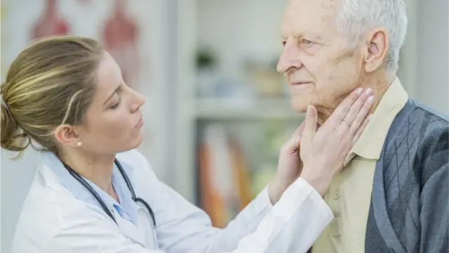 Um médico verifica os gânglios linfáticosprimeiro cassino no brasilum homem mais velho.