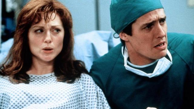 Os atores Hugh Grant e Julianne Moore com roupas de hospital e cara de pânico em cena do filme 'Nove Meses'