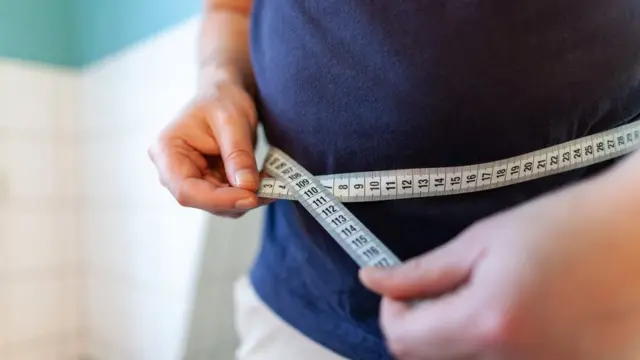 Homem obeso medindo circunferência da barriga