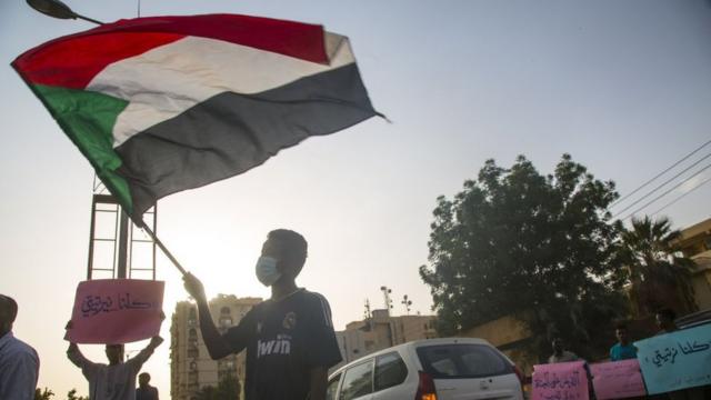 Мужчина размахивает суданским флагом в Хартуме (архивное фото)