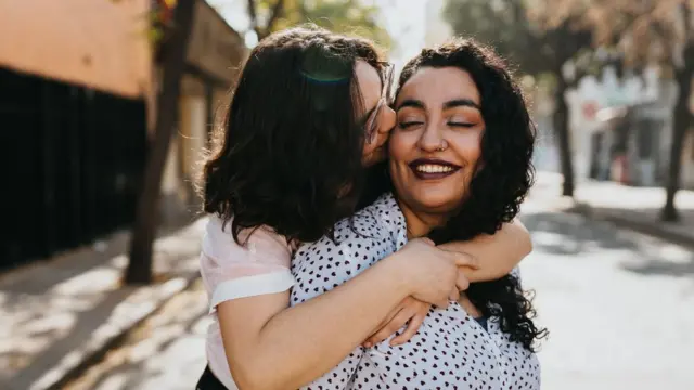 A lesbian couple is seen embracing on a street.