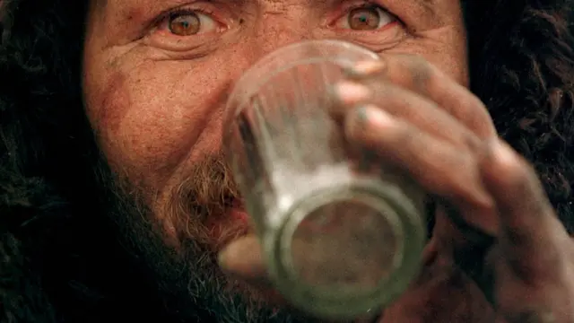 Мужчина пьет водку из граненого стакана