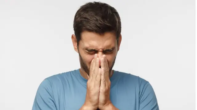 Hombre joven agarrándose la nariz en señal de dolor.